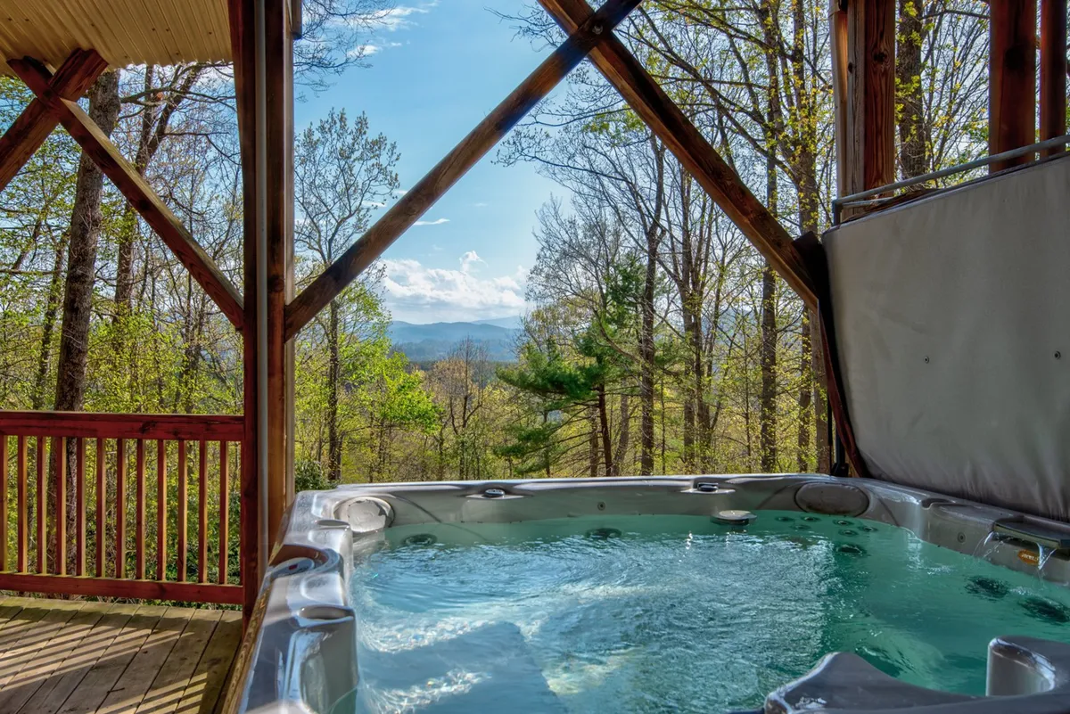 A wooden structure with a hot tub positioned to overlook sweeping mountain views, inviting guests to relax and soak in the scenery after a day of adventure. The peaceful setting is perfect for socializing or winding down as the sun sets.
